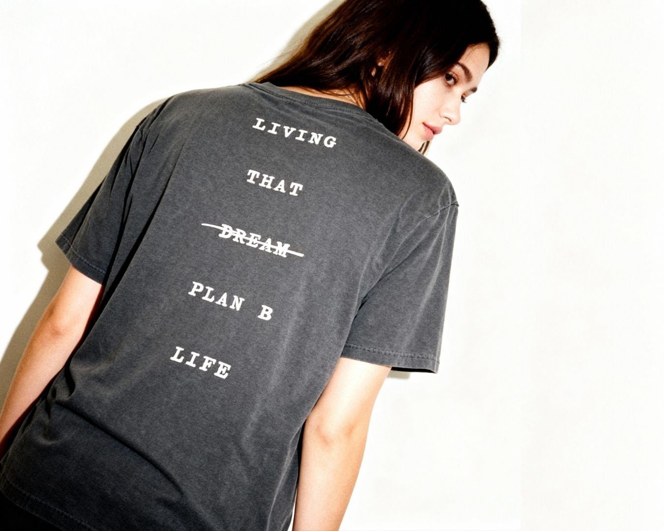 Person wearing a black t-shirt with motivational text on the back against a white background