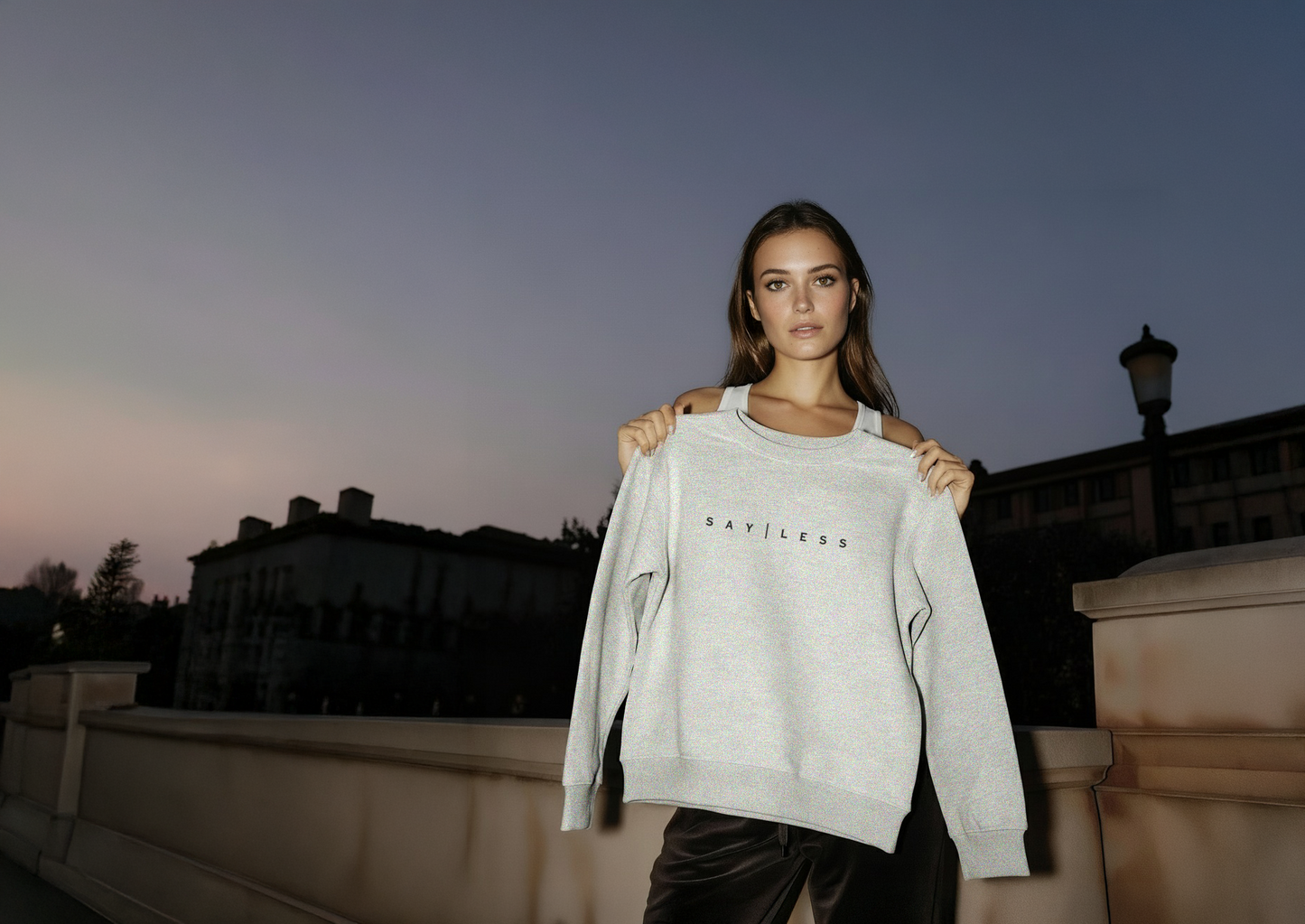 Woman holding a gray sweatshirt with 'Burberry' branding against a twilight sky.